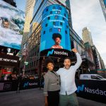 A photo of Twipes cofounders Elle and Al in front of the Nasdaq sign in Times Square