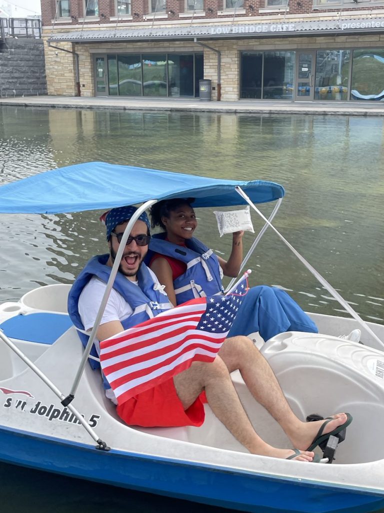 A photo of Twipes cofounders Al and Elle in a paddle boat holding up an American flag and a pack of Twipes to celebrate the company's expansion to America.