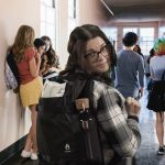 A photo of a woman walking down a college hallway with a pack of Twipes truly flushable, truly biodegradable wet wipes