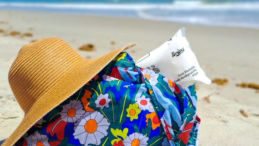 A photo of a beach hat, a flowery blue bag and a pack of Twipes on the beach (Twipes team photo)